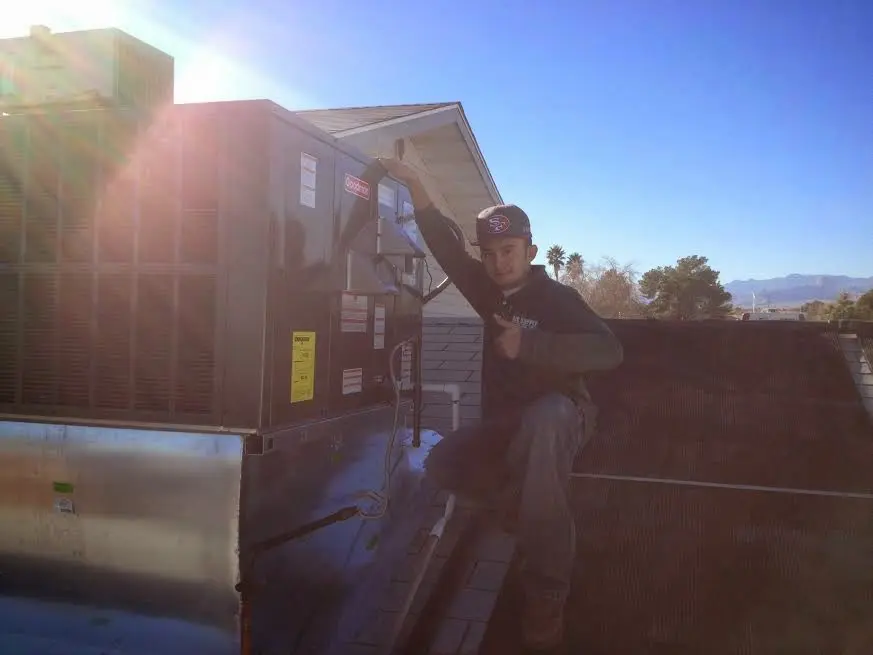 HVAC technician performing Heat Pump Repair on a rooftop unit in Louisville